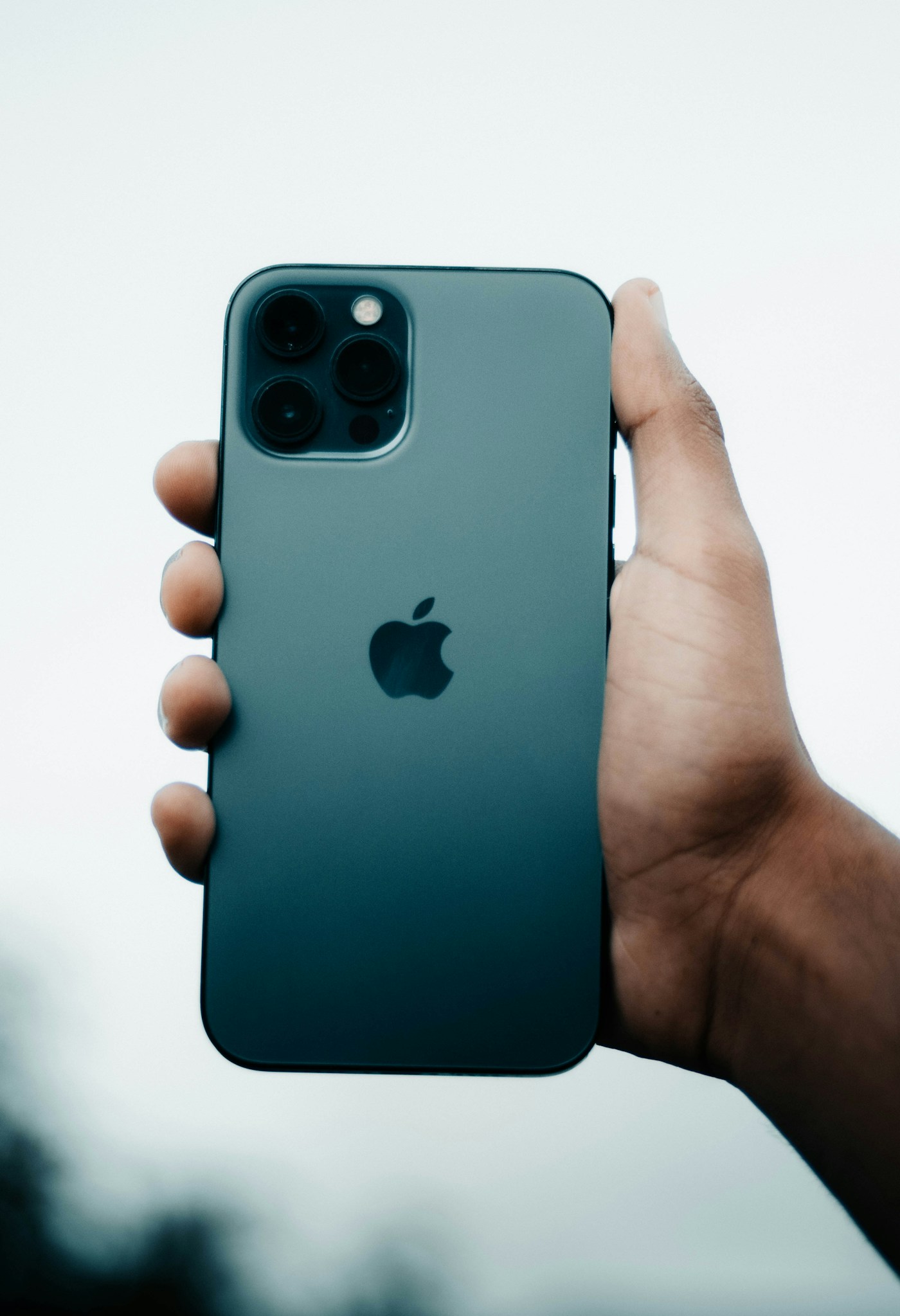 手持iPhone背面，展示摄像头与Apple标志